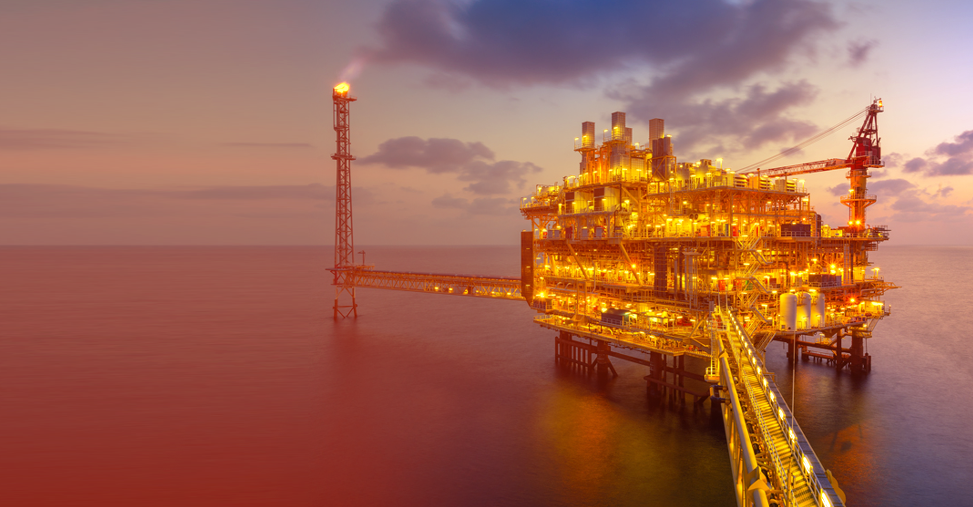 Offshore oil platform at sunset with supply vessel